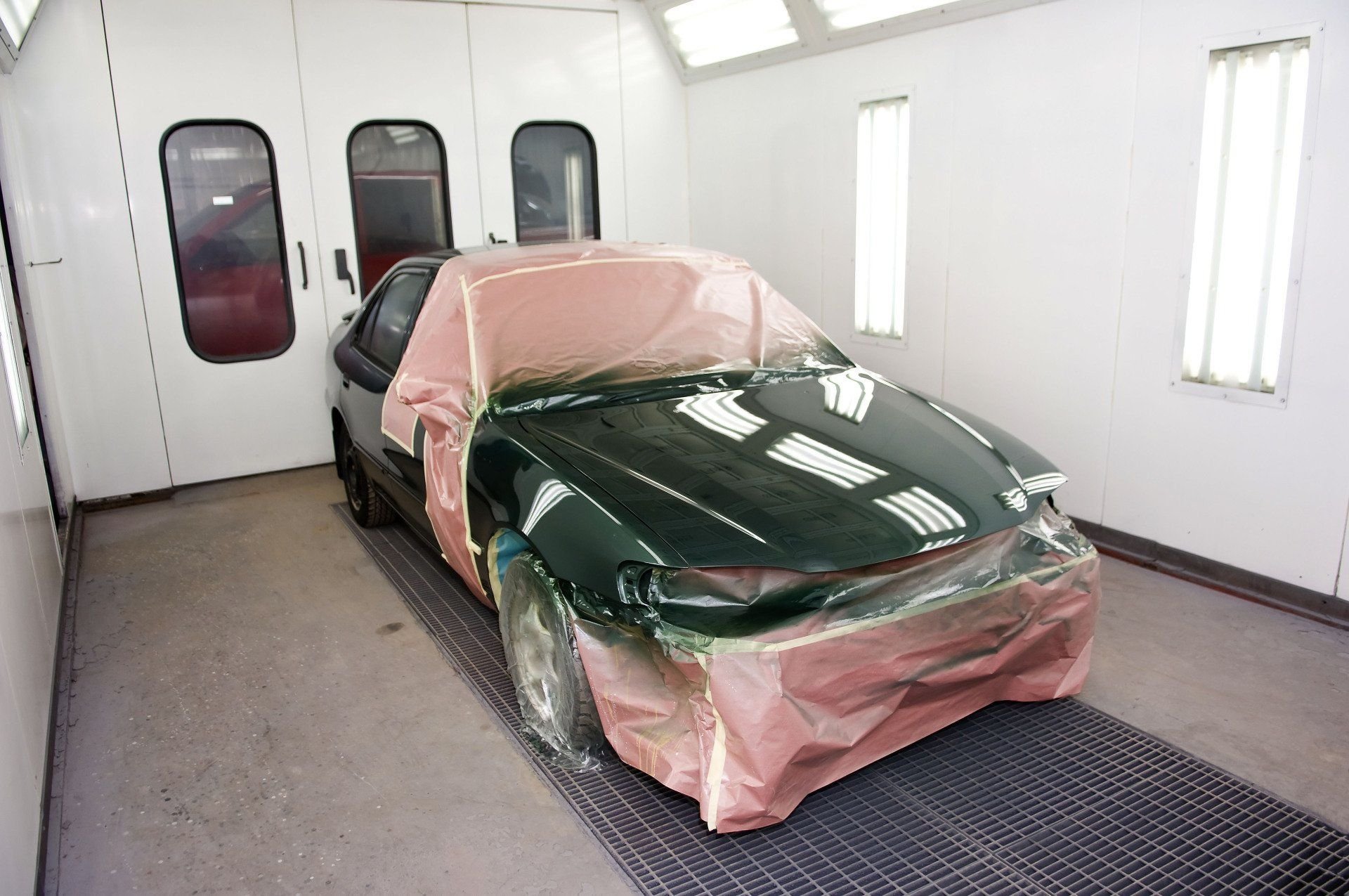 A masked vehicle prepared for refinishing in a paint booth